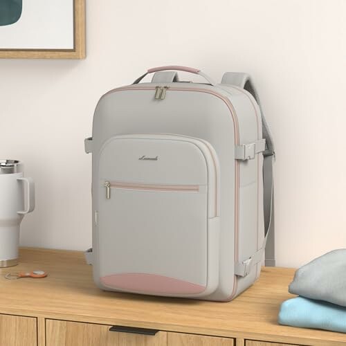 Light gray backpack with pink accents on a wooden desk.